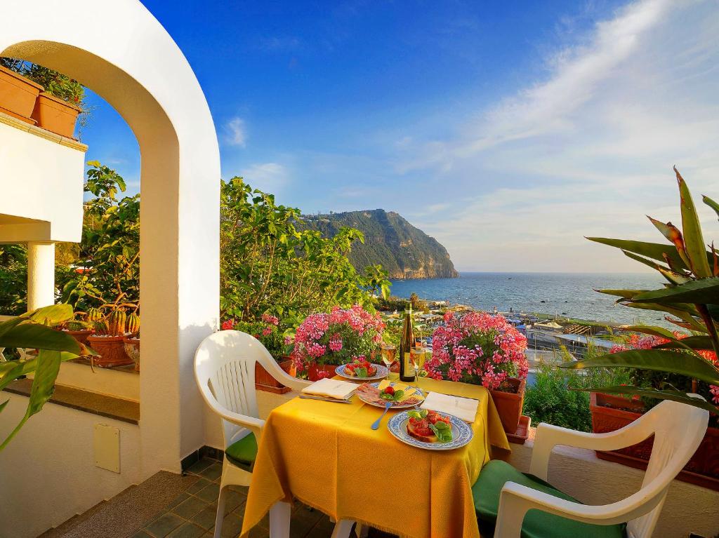 イスキアにあるアパルタメンティ カーサ デル ソーレのテーブルと椅子、海の景色を望むバルコニー