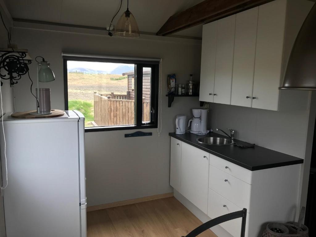 eine Küche mit einem weißen Kühlschrank und einem Fenster in der Unterkunft Hekla Nordicabin - Wild Cottage in Hella