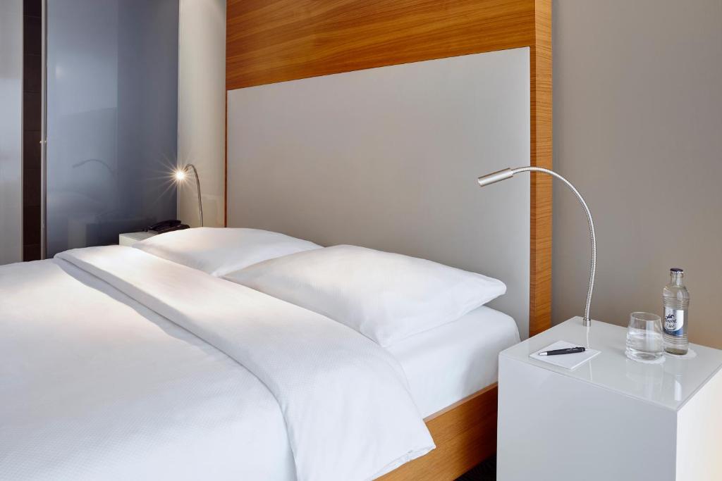 a bedroom with a white bed and a lamp at LÉGÈRE HOTEL Luxembourg in Luxembourg