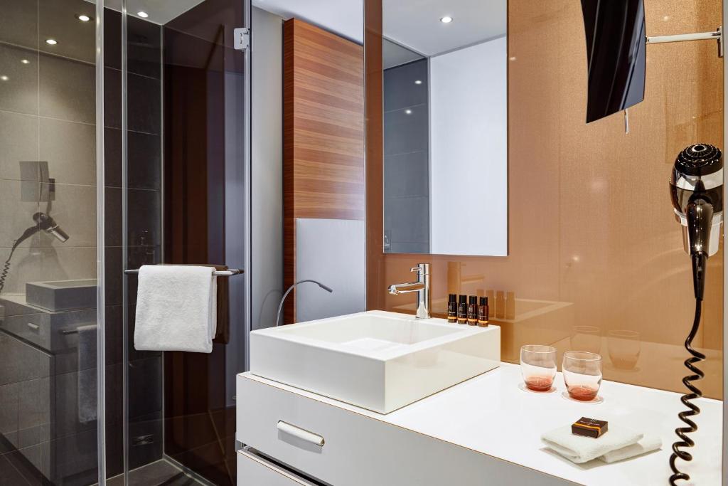 a bathroom with a white sink and a shower at LÉGÈRE HOTEL Luxembourg in Luxembourg