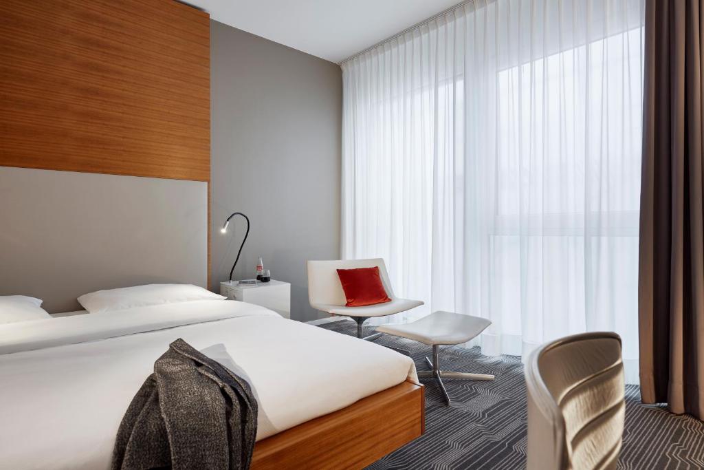 a bedroom with a bed and a chair and a window at LÉGÈRE HOTEL Luxembourg in Luxembourg