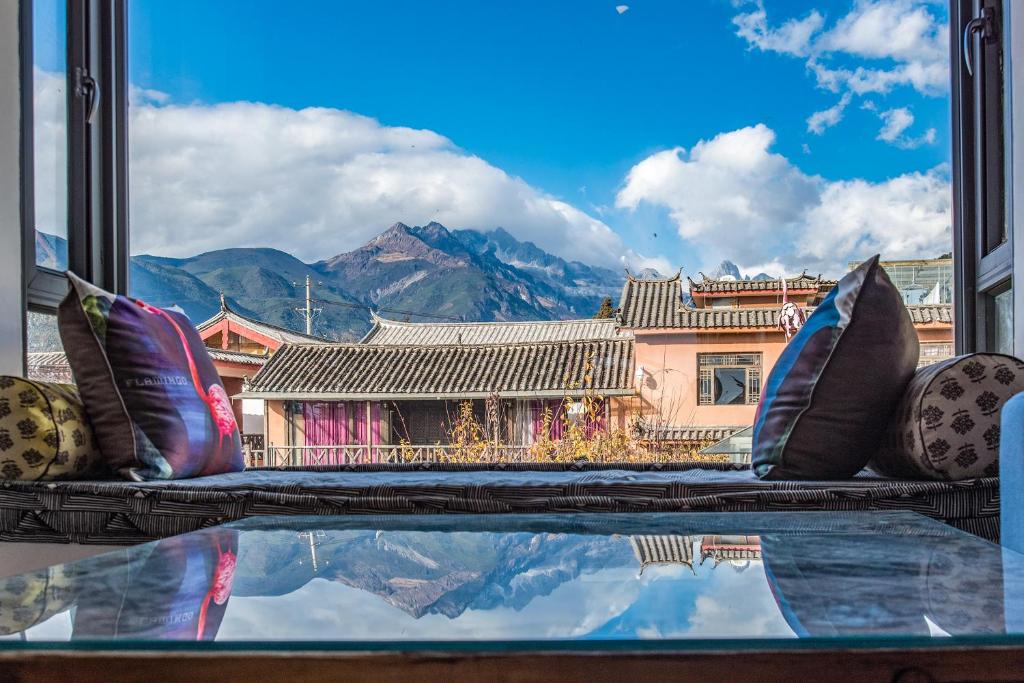 een raam met uitzicht op een berg bij Baisha Flamingo Hotel in Lijiang