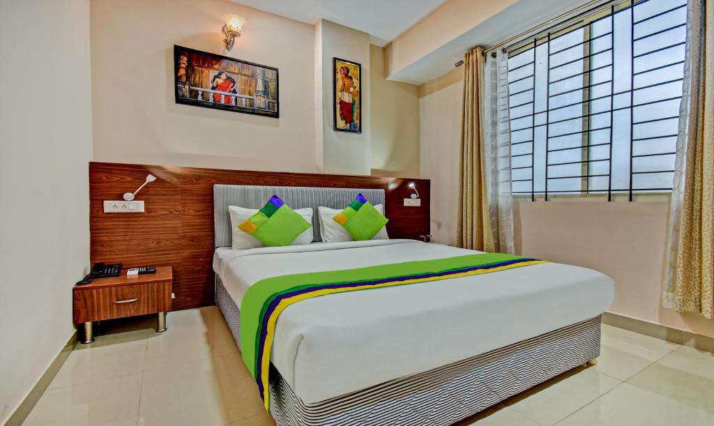 a bedroom with a large bed and a window at Treebo Trend Apple Tree Apartment & Suites in Bangalore