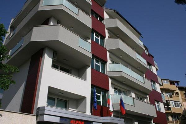 un edificio de apartamentos alto con banderas delante en ALPHA family HOTEL, en Blagoevgrad