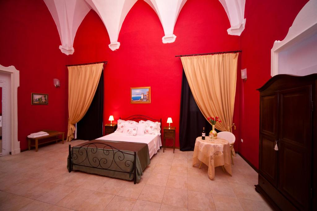 a bedroom with red walls and a bed and a table at B&B Dimora San Vincenzo in Gallipoli