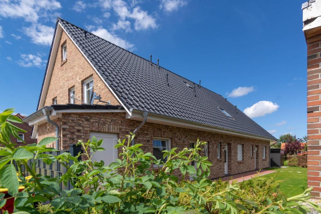 a brick house with a black roof at Ferienwohnung Nordseeliebe in Dornumersiel