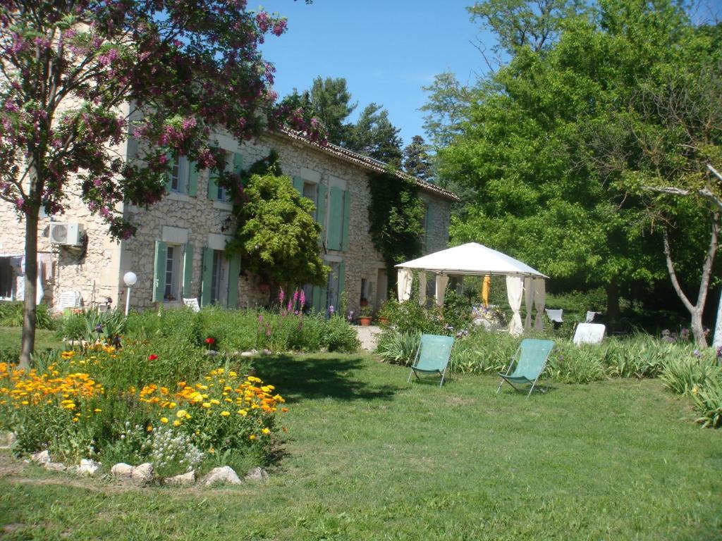 a house with two chairs in the yard at Le Mas d'Hermès in Plan-dʼOrgon