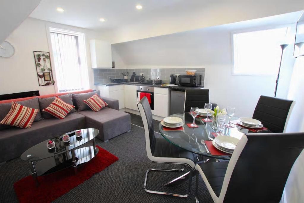 ein Wohnzimmer mit einem Tisch und einem Sofa in der Unterkunft Coast Accommodation Station Road Apartments in Blackpool