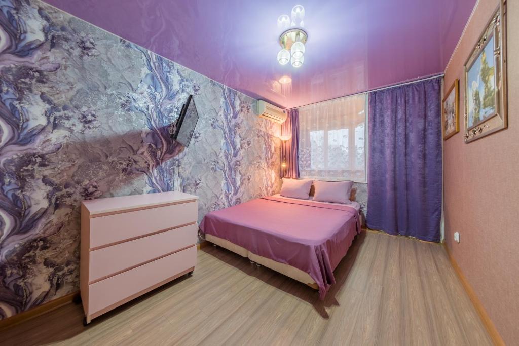 a bedroom with a bed and a purple wall at Двухкомнатные апартаменты рядом с вокзалом in Sochi