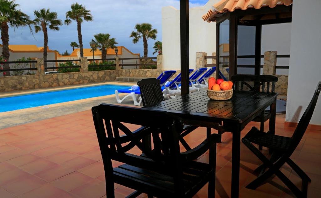 un tavolo nero con sedie e frutta accanto a una piscina di Vip Villas - Caleta Dorada a Caleta De Fuste