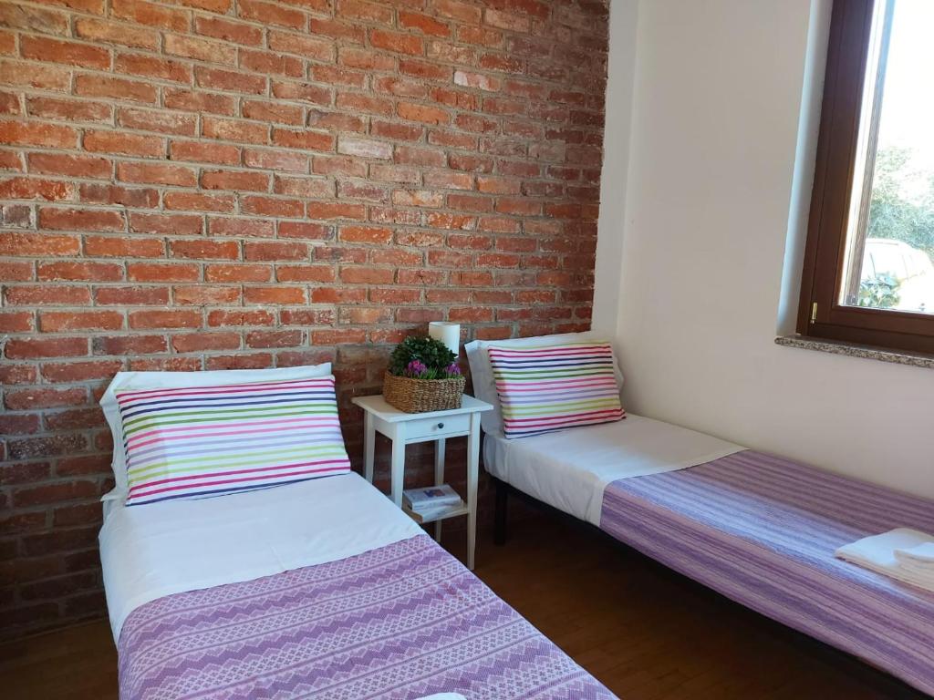 2 Betten in einem Zimmer mit Ziegelwand in der Unterkunft Corte Borromeo - Fiera Milano Rho in Rho