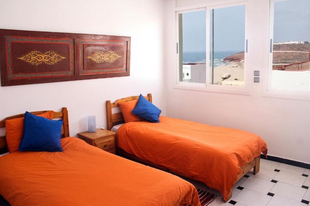 two beds in a room with a view of the ocean at Ifni Surf Hostal in Sidi Ifni