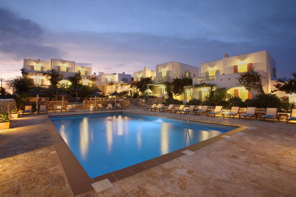 a swimming pool with chairs and buildings in the background at Aeolos Hotel in Koufonisia