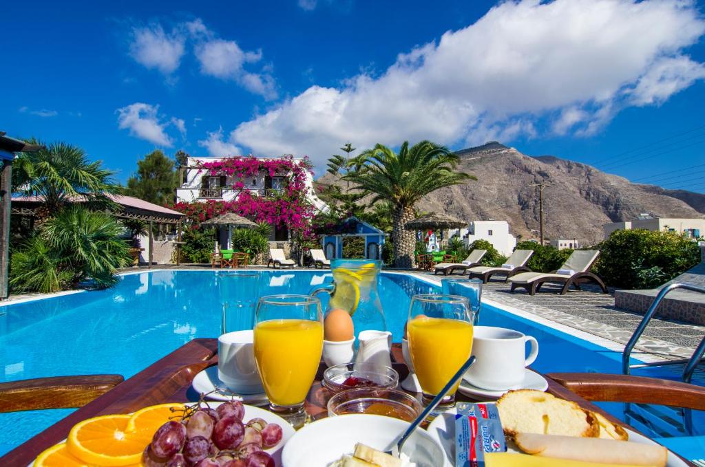 a table with food and drinks next to a swimming pool at Holiday Beach Resort Santorini in Perivolos