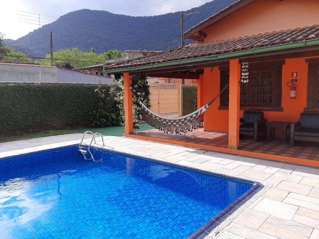 a swimming pool with a hammock next to a house at FANTÁSTICA CASA COM ÁREA DE PISCINA até 10 PESSOAS em MARESIAS SÃO SEBASTIÃO in Maresias