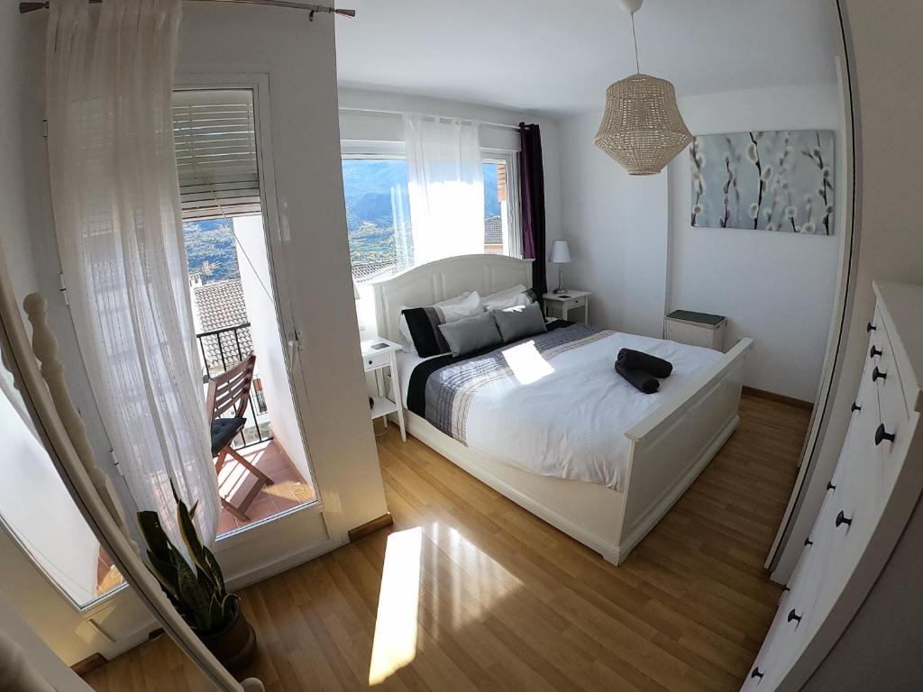 1 dormitorio con cama y vistas a un balcón en Casa San Tomas, en Güéjar-Sierra