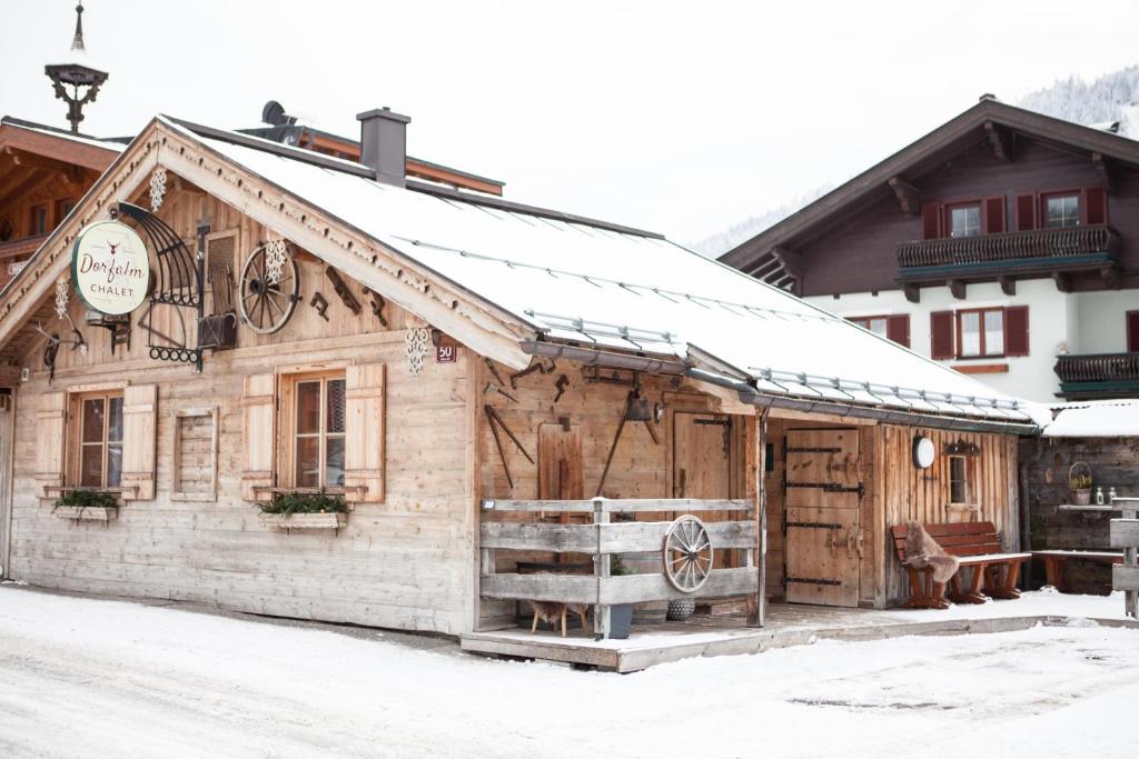 a wooden building with snow on the roof at Chalet Dorfalm in Maria Alm am Steinernen Meer
