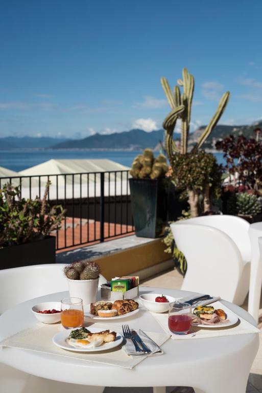 a white table with plates of food on a balcony at Hotel Albatros Varigotti in Varigotti