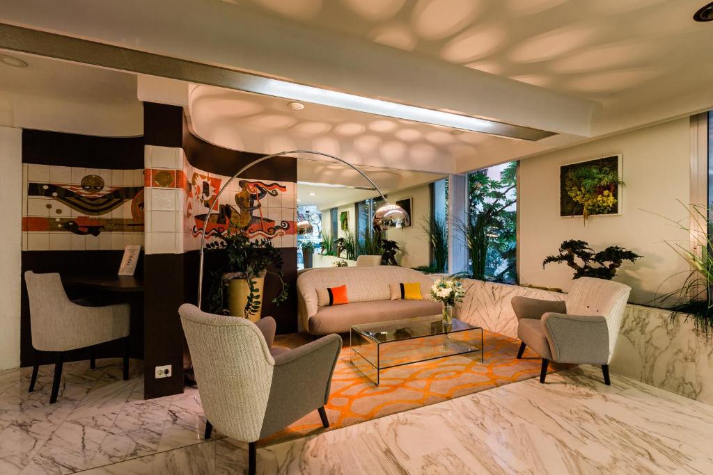 a living room with a couch and chairs at Hôtel Hélios in Juan-les-Pins