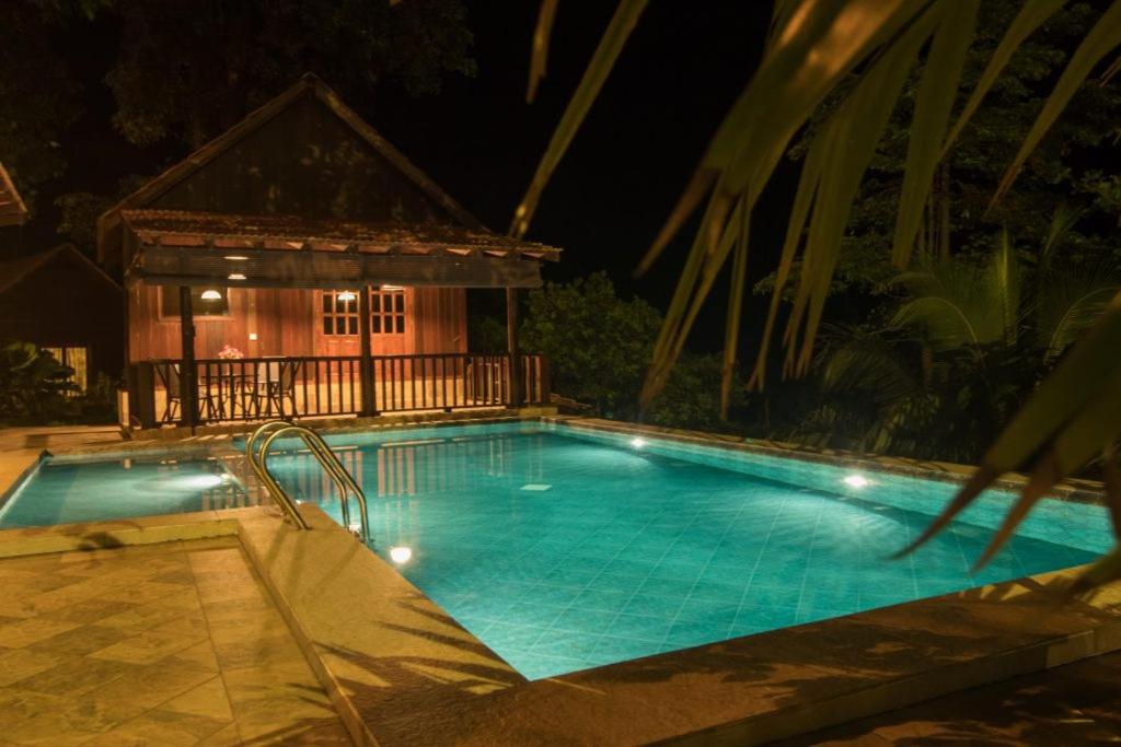 a swimming pool at night with a house in the background at Deserenity in Seremban