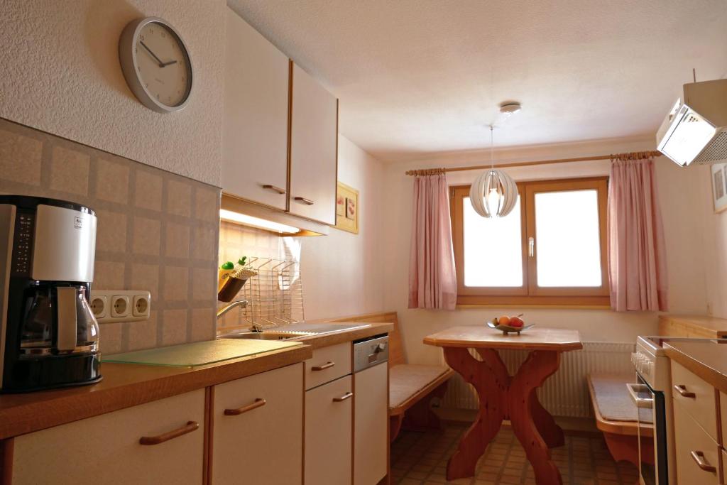 une cuisine avec une table et une horloge murale dans l'établissement Haus Maringele, à Nesselwängle