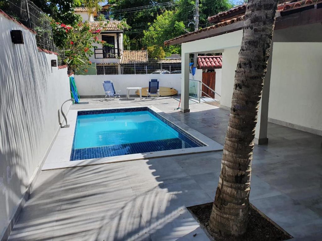 a swimming pool with a palm tree in a yard at Casa do Tio Eri - Geribá - 100 metros da Praia in Búzios
