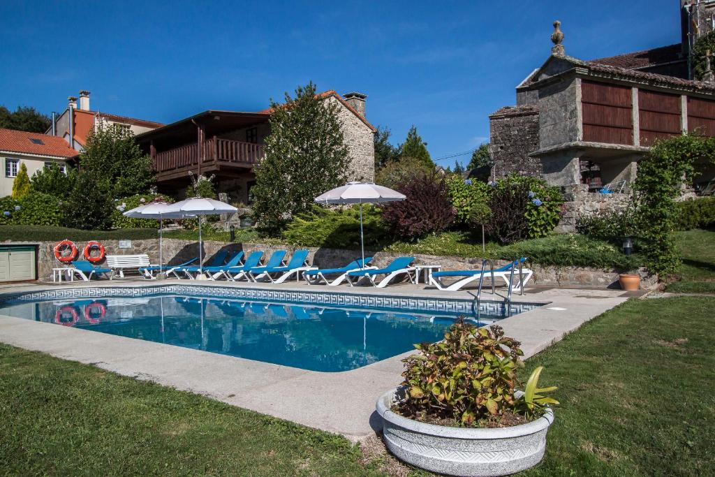 una piscina con sillas y sombrillas en un patio en Casas Rurales A Peregrina, en Codeseda