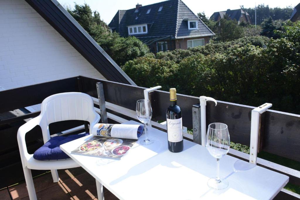 a white table with two glasses and a bottle of wine at C-Haus Cordula, App 41 in Wenningstedt