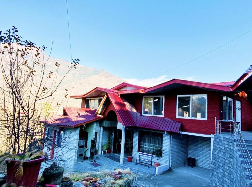 a red house with a mountain in the background at Hotel Sanjeevny in Bajaura
