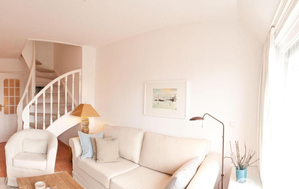 a white living room with a white couch and a chair at C-Haus Constanze, App 46 in Wenningstedt