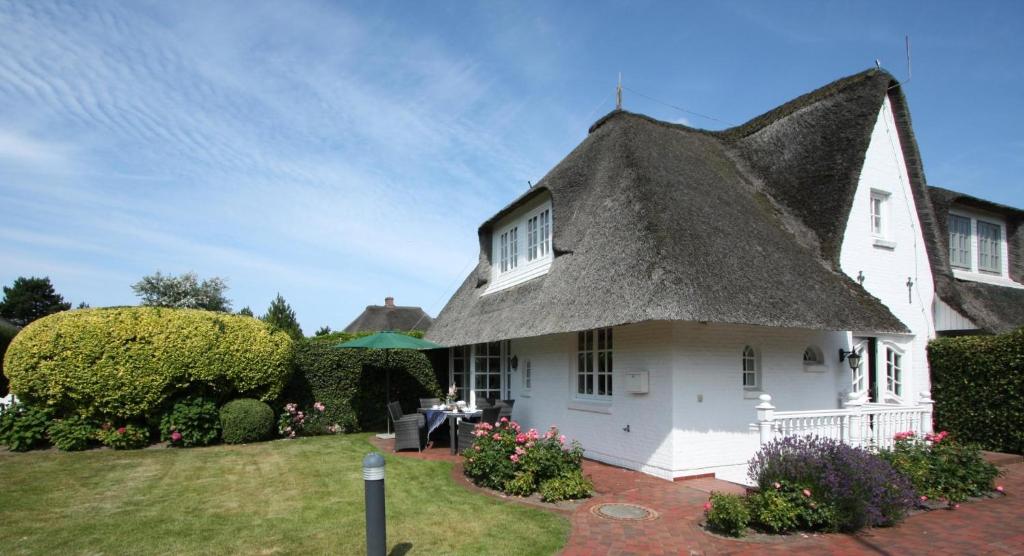 a white house with a thatched roof at Rosenhaus unter Reet in Kampen