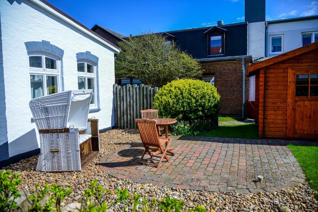 eine Terrasse mit 2 Stühlen und einem Tisch vor einem Haus in der Unterkunft Sölring Hüs, App 3 in Wenningstedt-Braderup