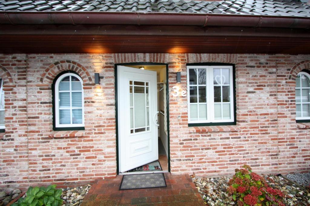 a brick house with a white door and windows at Ferienhaus Gartenweg in Tinnum