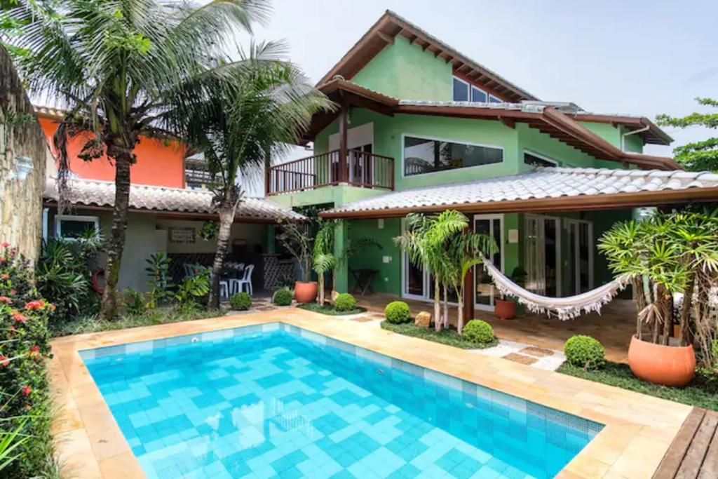 a villa with a swimming pool in front of a house at UBATUBA PRAIA DO SAPE - bela casa em condominio - 01 Quadra da Praia, Wifi, Piscina, Churrasqueira e Forno de Pizza in Ubatuba