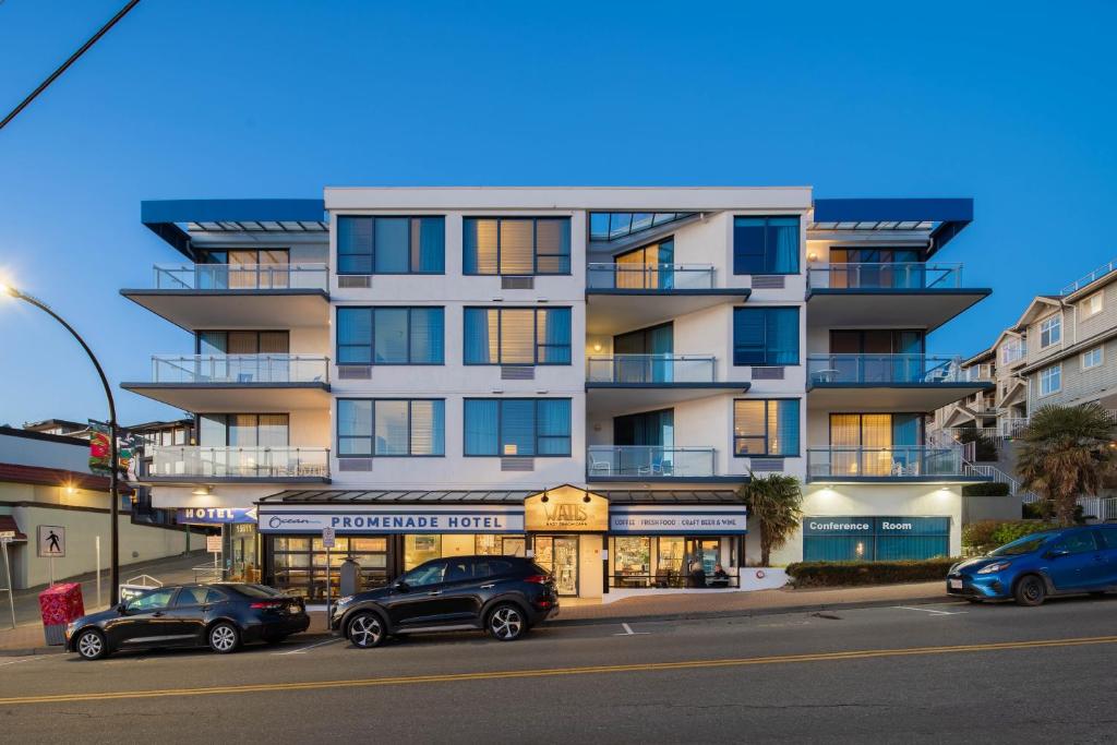 een hoog wit gebouw met auto's geparkeerd voor het bij Ocean Promenade Hotel in White Rock