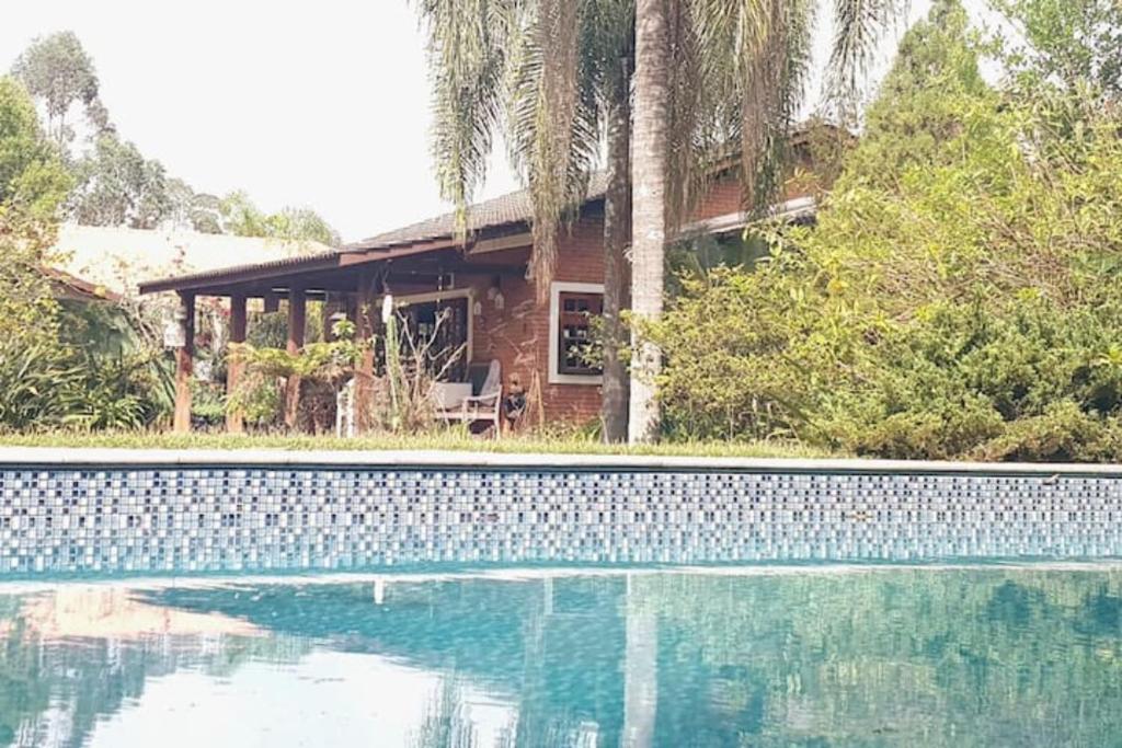 a house with a swimming pool in front of a house at LINDA CHACARA EM CONDO A 40 MIN DE SP com piscina climatizada, churrasqueira, wifi, 5 quartos e muita natureza in Cajamar