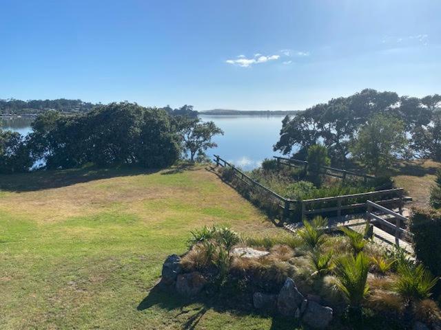 un campo con una valla y un cuerpo de agua en Dune View Accommodation en Mangawhai