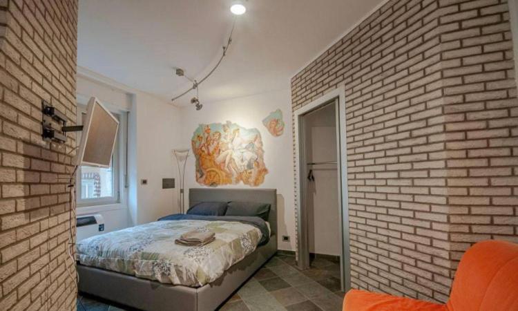 - une chambre avec un lit et un mur en briques dans l'établissement Dormire in Centro Trieste Studio Galleria 16 cavana, à Trieste