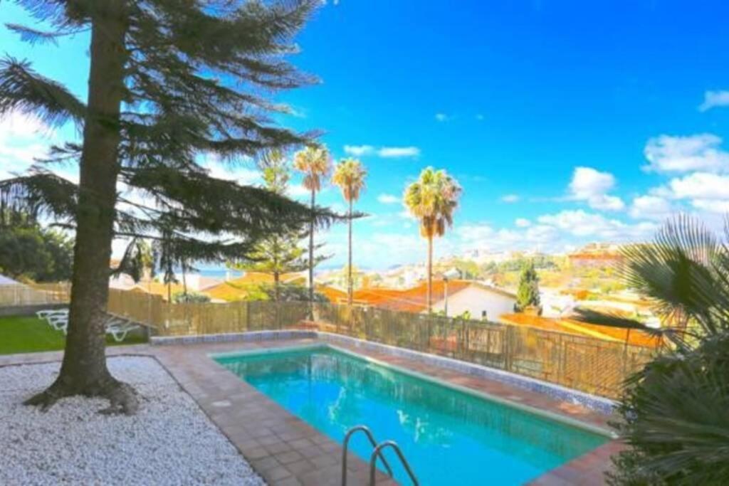 einen Pool mit einem Zaun und Palmen in der Unterkunft VILLA CERCA DE LA PLAYA,PISCINA PRIVADA,BBq in Málaga