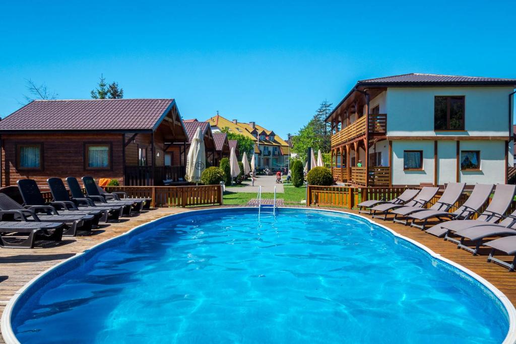 a large swimming pool with chairs and a house at Dom Wczasowy Laguna in Dąbki