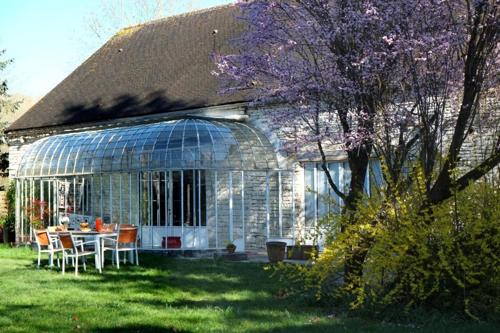 a glass house with a table and chairs in the yard at Chez Séverine & Edward in Sainte-Vertu