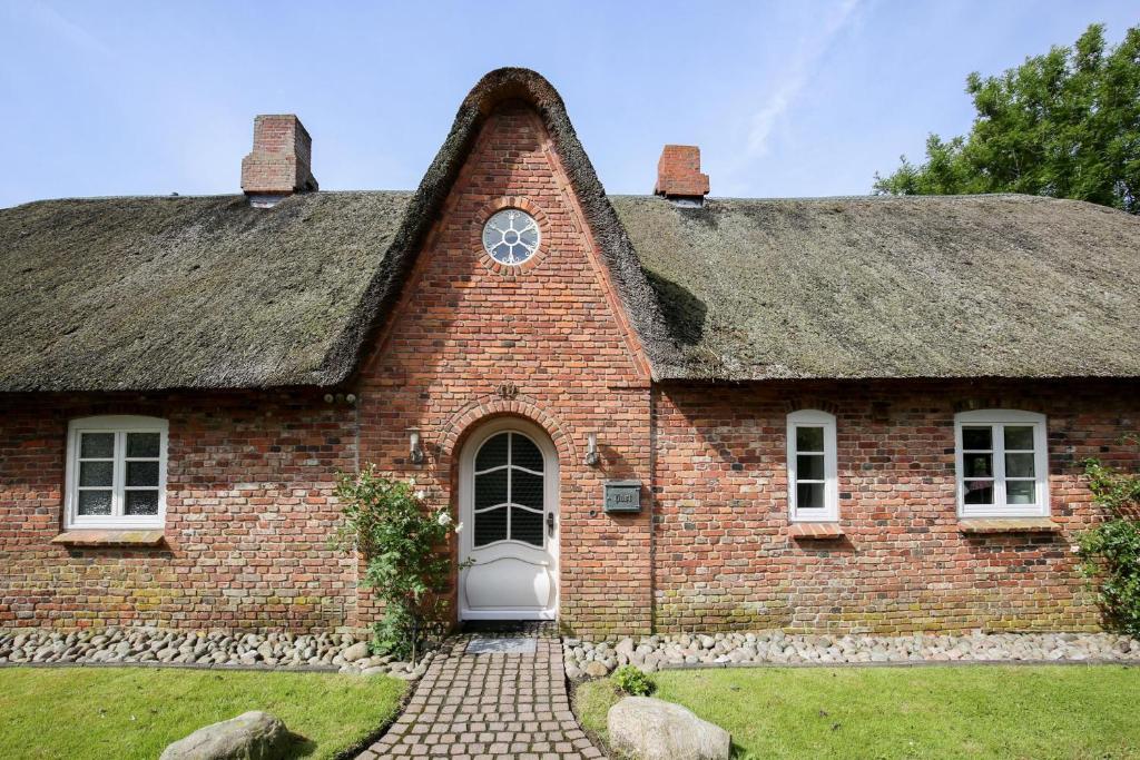 Risum-LindholmにあるLandhaus Risumの茅葺き屋根の古いレンガ造りの家