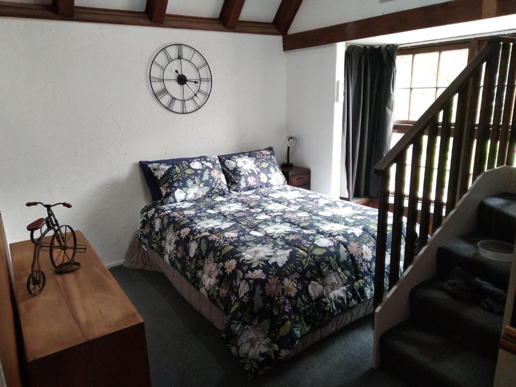 但尼丁的住宿－Arden Country House - The Chalet Bed and Breakfast，卧室配有一张床,墙上挂着一个钟