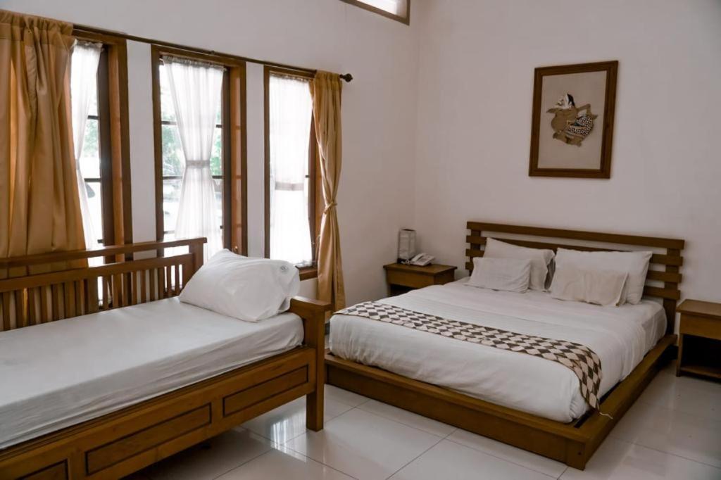 a bedroom with two beds and two windows at Grand Cepu Hotel in Cepu