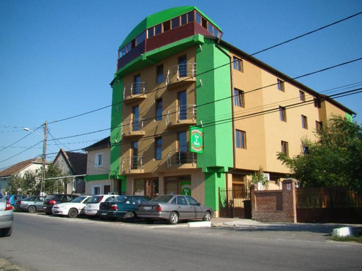 un edificio verde con coches aparcados delante de él en Pensiunea Ivu si Raul en Giroc
