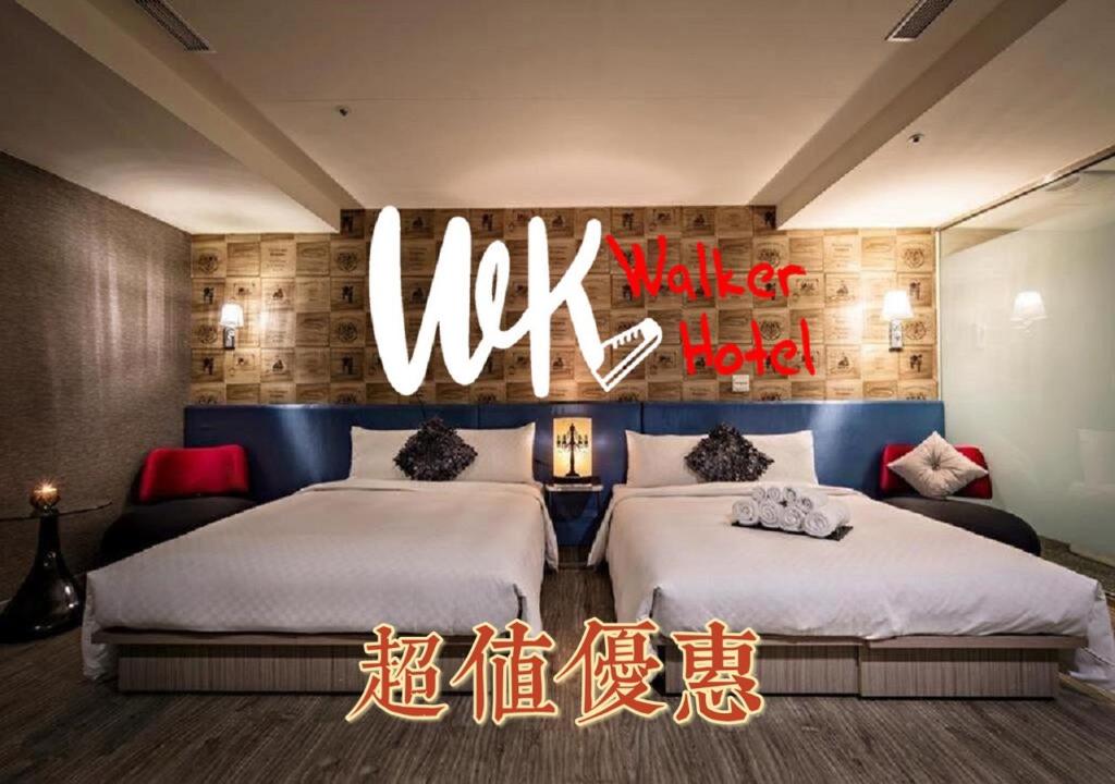 two beds in a room with a sign that reads uk market hotel at Walker Hotel - Zhengyi in Taipei