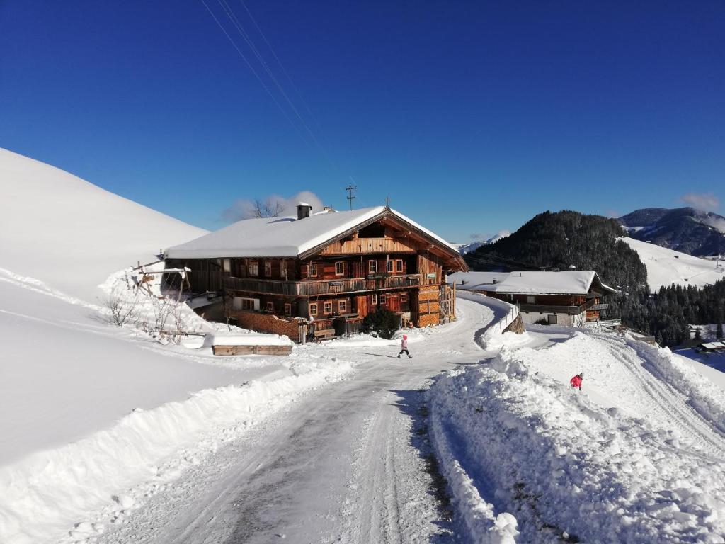 a log cabin in the snow with a road in front at Tradlhof in Thierbach