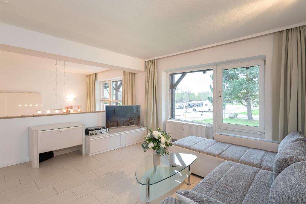 ein Wohnzimmer mit einem Sofa und einem TV in der Unterkunft Golfresidenz Wohnung B004 in Grömitz