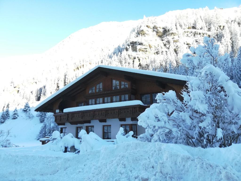 un edificio cubierto de nieve frente a una montaña en Haus Alpengruss, en Sankt Leonhard im Pitztal