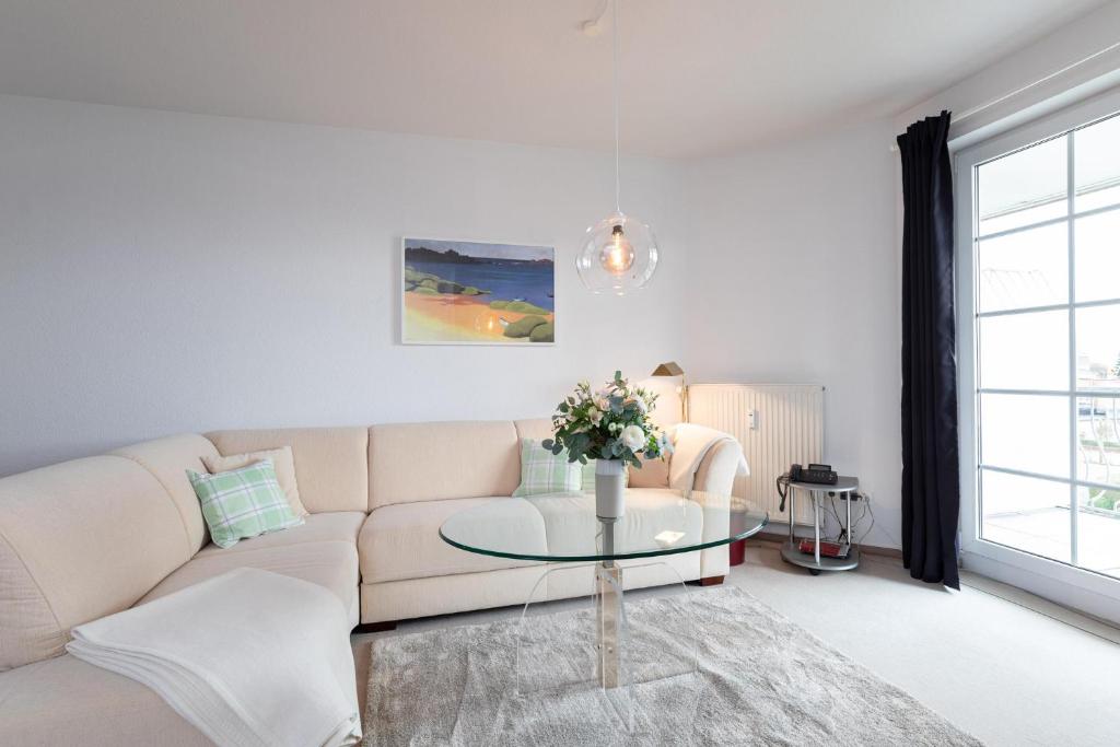 ein Wohnzimmer mit einem Sofa und einem Glastisch in der Unterkunft Commodore Wohnung 44 in Grömitz